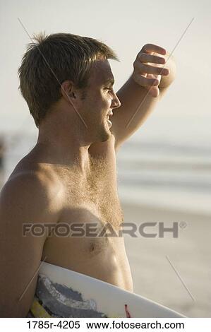 Surfer dude standing on beach with a surfboard View Large Photo Image Stock Photography - Surfer dude standing on beach with a surfboard. Fotosearch