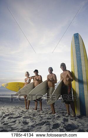 Surfer dudes and girl posing on beach at sunrise with surfboards View Large Photo Image Picture - Surfer dudes and girl posing on beach at sunrise with surfboards. Fotosearch
