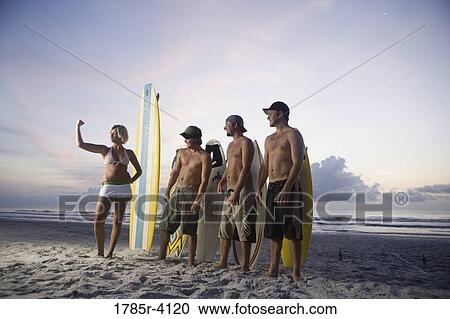 Surfer dudes and girl posing on beach at sunrise with surfboards View Large Photo Image Stock Image - Surfer dudes and girl posing on beach at sunrise with surfboards. Fotosearch