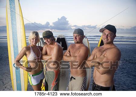 Surfer dudes and girl posing on beach at sunrise with surfboards View Large Photo Image Stock Image - Surfer dudes and girl posing on beach at sunrise with surfboards. Fotosearch