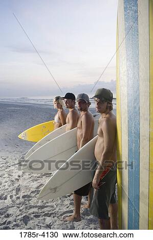 Surfer dudes and girl posing on beach at sunrise with surfboards View Large Photo Image Stock Image - Surfer dudes and girl posing on beach at sunrise with surfboards. Fotosearch