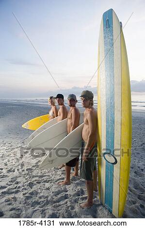Surfer dudes and girl posing on beach at sunrise with surfboards View Large Photo Image Stock Image - Surfer dudes and girl posing on beach at sunrise with surfboards. Fotosearch