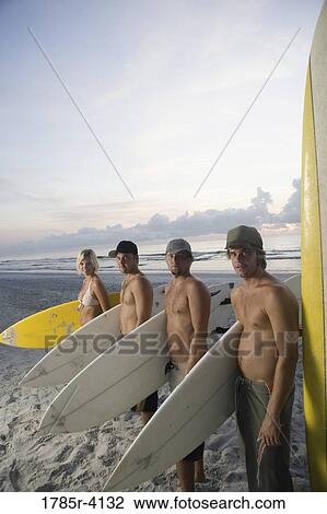 Surfer dudes and girl posing on beach at sunrise with surfboards View Large Photo Image Stock Image - Surfer dudes and girl posing on beach at sunrise with surfboards. Fotosearch