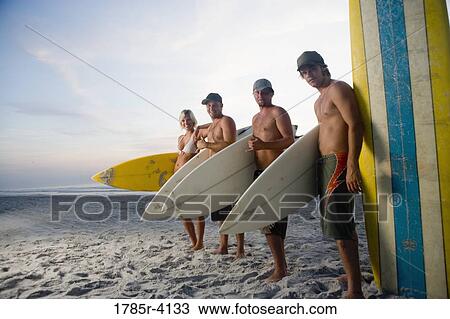 Surfer dudes and girl posing on beach at sunrise with surfboards View Large Photo Image Stock Image - Surfer dudes and girl posing on beach at sunrise with surfboards. Fotosearch