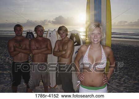 Surfer dudes and girl posing on beach at sunrise with surfboards View Large Photo Image Stock Image - Surfer dudes and girl posing on beach at sunrise with surfboards. Fotosearch
