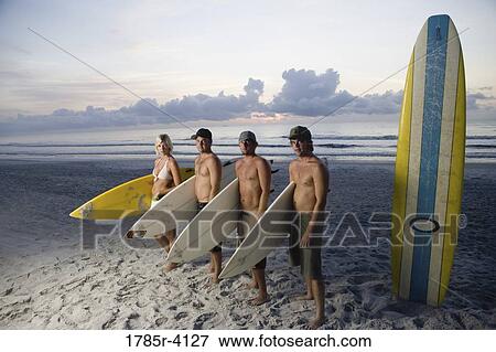 Surfer dudes and girl posing on beach at sunrise with surfboards View Large Photo Image Stock Photo - Surfer dudes and girl posing on beach at sunrise with surfboards. Fotosearch