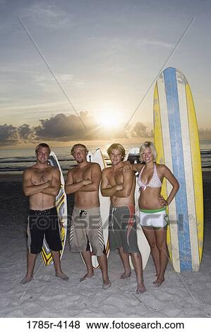 Surfer dudes and girl posing on beach at sunrise with surfboards View Large Photo Image Stock Photo - Surfer dudes and girl posing on beach at sunrise with surfboards. Fotosearch