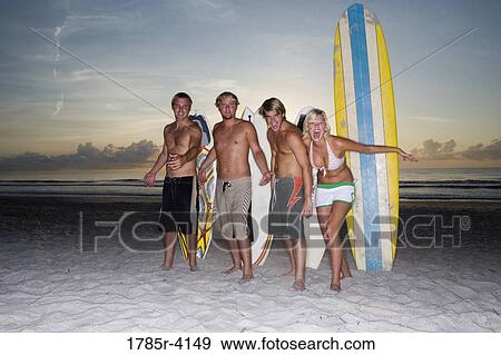 Surfer dudes and girl posing on beach at sunrise with surfboards View Large Photo Image Stock Photo - Surfer dudes and girl posing on beach at sunrise with surfboards. Fotosearch