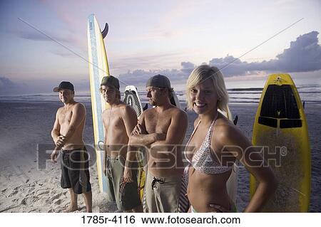 Surfer dudes and girl posing on beach at sunrise with surfboards View Large Photo Image Stock Photograph - Surfer dudes and girl posing on beach at sunrise with surfboards. Fotosearch