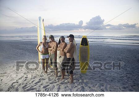 Surfer dudes and girl posing on beach at sunrise with surfboards View Large Photo Image Stock Photograph - Surfer dudes and girl posing on beach at sunrise with surfboards. Fotosearch