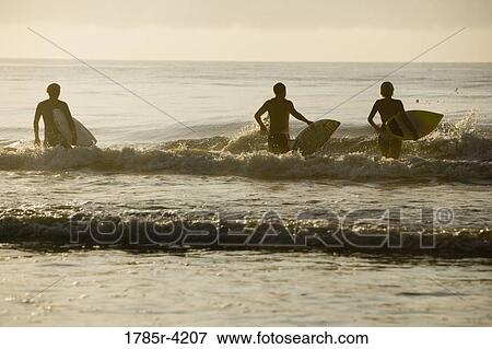Surfer dudes and girl running into surf with surfboards View Large Photo Image Stock Photo - Surfer dudes and girl running into surf with surfboards. Fotosearch