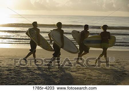 Surfer dudes and girl running on beach with surfboards View Large Photo Image Stock Image - Surfer dudes and girl running on beach with surfboards. Fotosearch