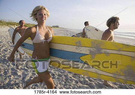 Surfer dudes and girl running towards surf with surfboards View Large Photo Image Picture - Surfer dudes and girl running towards surf with surfboards. Fotosearch