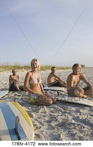 Surfer dudes and girl sitting on beach with surfboards View Large Photo Image Stock Image - Surfer dudes and girl sitting on beach with surfboards. Fotosearch
