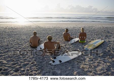 Surfer dudes and girl sitting on beach at sunrise with surfboards View Large Photo Image Stock Image - Surfer dudes and girl sitting on beach at sunrise with surfboards. Fotosearch