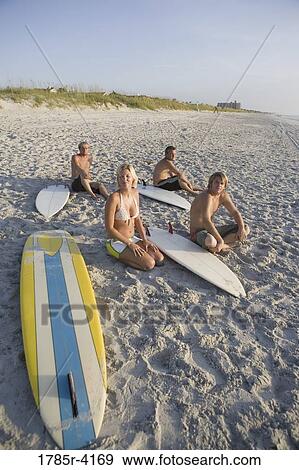Surfer dudes and girl sitting on beach with surfboards View Large Photo Image Stock Photo - Surfer dudes and girl sitting on beach with surfboards. Fotosearch