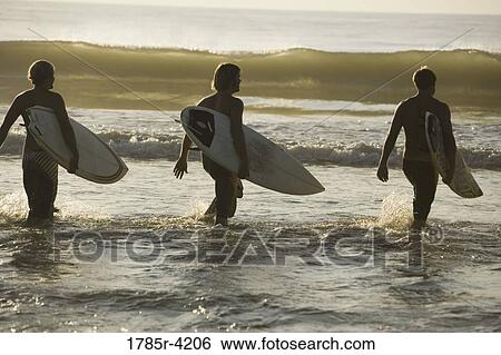 Surfer dudes running into surf with surfboards View Large Photo Image Stock Photograph - Surfer dudes running into surf with surfboards. Fotosearch