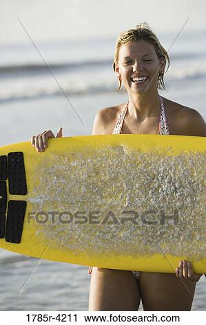 Surfer girl standing on beach with a surfboard View Large Photo Image Stock Image - Surfer girl standing on beach with a surfboard. Fotosearch