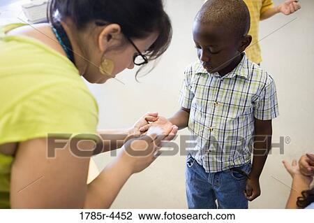 Teacher cleaning boy's hands with a napkin View Large Photo Image Stock Image - Teacher cleaning boy's hands with a napkin. Fotosearch