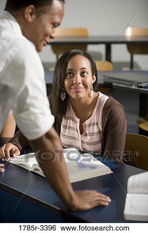 Teacher conversing with student in classroom View Large Photo Image Stock Photograph - Teacher conversing with student in classroom. Fotosearch