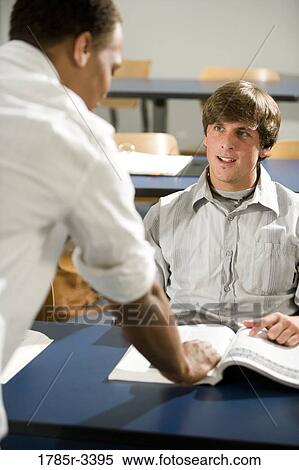 Teacher conversing with student in classroom View Large Photo Image Stock Photography - Teacher conversing with student in classroom. Fotosearch