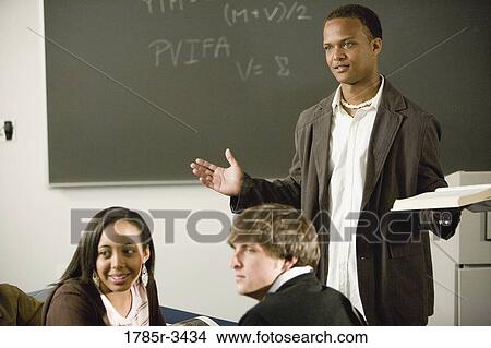 Teacher gesturing to students in the classroom View Large Photo Image Picture - Teacher gesturing to students in the classroom. Fotosearch