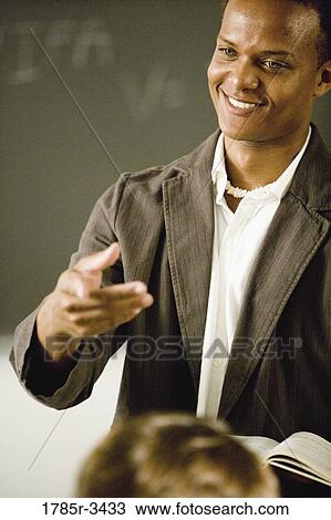 Teacher gesturing to students in the classroom View Large Photo Image Stock Image - Teacher gesturing to students in the classroom. Fotosearch