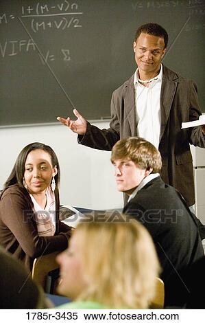 Teacher gesturing to students in the classroom View Large Photo Image Stock Photography - Teacher gesturing to students in the classroom. Fotosearch