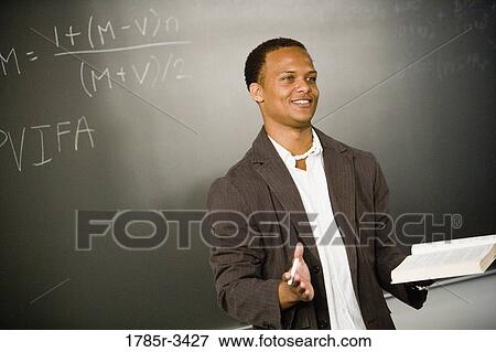 Teacher in front of chalk board teaching in the classroom View Large Photo Image Stock Photo - Teacher in front of chalk board teaching in the classroom. Fotosearch