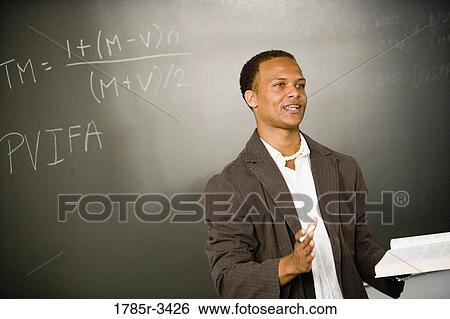 Stock Photograph - Teacher in front of chalk board teaching in the classroom. Fotosearch