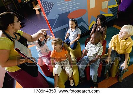 Stock Image - Teacher reading to group of young children. Fotosearch