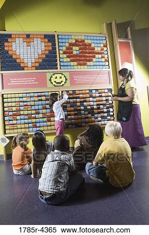 Stock Photography - Teacher shows children an interactive art display. Fotosearch