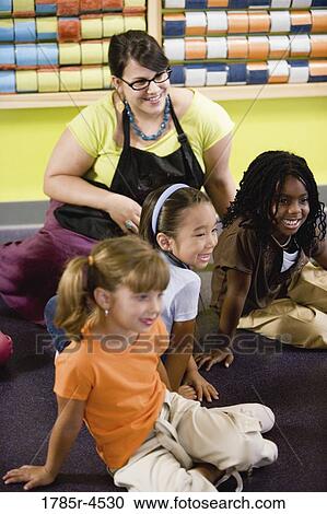 Teacher sitting and posing with students in a colorful classroom View Large Photo Image Stock Image - Teacher sitting and posing with students in a colorful classroom. Fotosearch