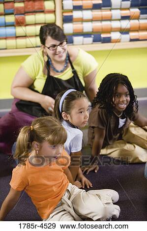 Teacher sitting and posing with students in a colorful classroom View Large Photo Image Stock Photo - Teacher sitting and posing with students in a colorful classroom. Fotosearch