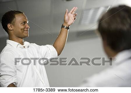 Stock Photo - Teacher standing in the classroom gesturing towards class. Fotosearch