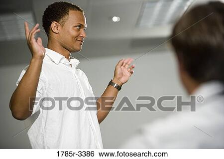 Teacher standing in the classroom gesturing towards class View Large Photo Image Stock Photograph - Teacher standing in the classroom gesturing towards class. Fotosearch