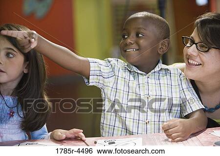 Stock Photograph - Teacher with happy young boy pointing at something. Fotosearch