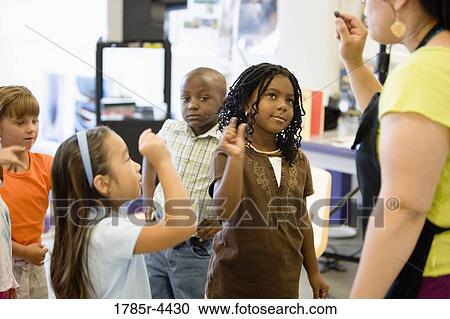 Teacher with her young students raising hands View Large Photo Image Stock Image - Teacher with her young students raising hands. Fotosearch