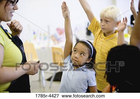 Teacher with her young students raising hands View Large Photo Image Stock Photo - Teacher with her young students raising hands. Fotosearch