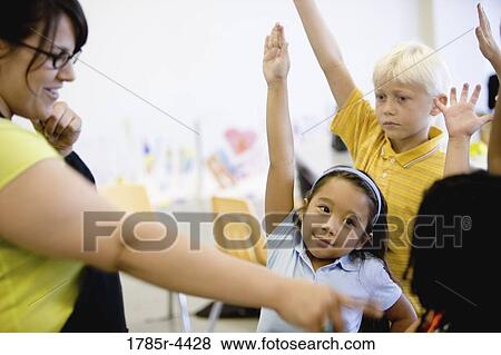 Teacher with her young students raising hands View Large Photo Image Stock Photo - Teacher with her young students raising hands. Fotosearch