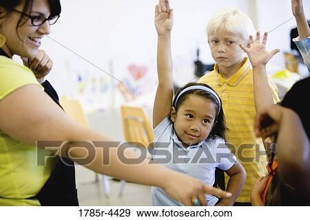 Teacher with her young students raising hands View Large Photo Image Stock Photo - Teacher with her young students raising hands. Fotosearch