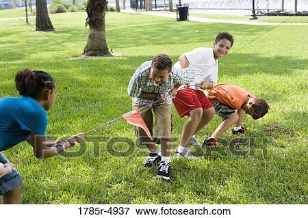 Stock Photo - Three boys and a girl pulling hard at a tug-of-war. Fotosearch