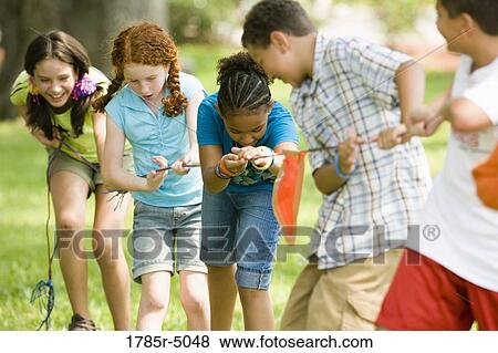Three boys challenging three girls at tug-of-war at a park View Large Photo Image Stock Photo - Three boys challenging three girls at tug-of-war at a park. Fotosearch