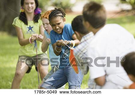 Stock Photo - Three boys challenging three girls at tug-of-war at a park. Fotosearch