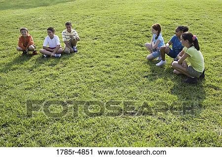 Three boys sitting opposite three girls on grass at a park View Large Photo Image Stock Image - Three boys sitting opposite three girls on grass at a park. Fotosearch