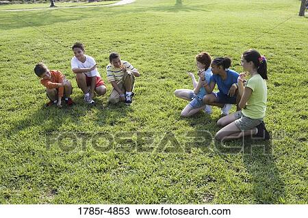 Three boys sitting opposite three girls on grass at a park View Large Photo Image Stock Image - Three boys sitting opposite three girls on grass at a park. Fotosearch