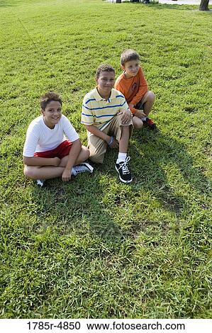 Three boys sitting together on grass at a park View Large Photo Image Stock Image - Three boys sitting together on grass at a park. Fotosearch