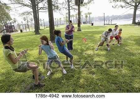 Three girls challenging three boys at a tug-of-war refereed by their teacher View Large Photo Image Stock Image - Three girls challenging three boys at a tug-of-war refereed by their teacher. Fotosearch