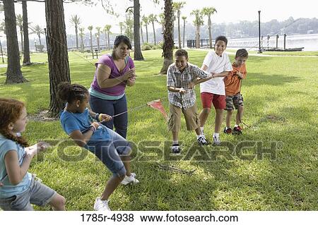 Three girls challenging three boys at a tug-of-war refereed by their teacher View Large Photo Image Stock Photo - Three girls challenging three boys at a tug-of-war refereed by their teacher. Fotosearch