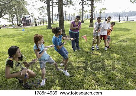 Three girls challenging three boys at a tug-of-war refereed by their teacher View Large Photo Image Stock Photo - Three girls challenging three boys at a tug-of-war refereed by their teacher. Fotosearch
